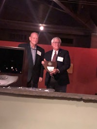 two men standing next to each other holding a plaque