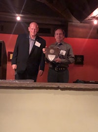 two men standing next to each other holding a plaque
