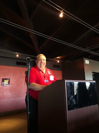a woman in a red shirt standing at a podium