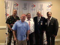 a group of men posing for a picture in front of a banner