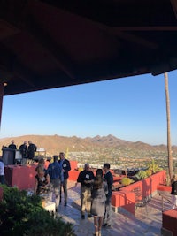 a group of people standing on a patio with a view of the mountains